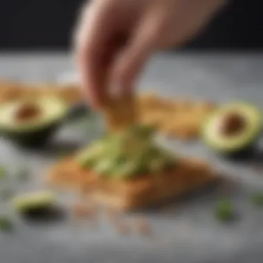 Vege Cracker with Avocado Topping Close-up of a hand reaching for a vege cracker topped with avocado and herbs