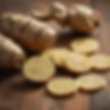 Fresh ginger root and slices laid on a wooden surface.
